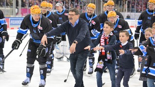 Der Eishockey-Manager der Fischtown Pinguins miot Spielern udn Kindern auf dem Eis