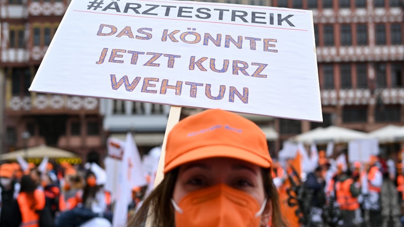 Eine Frau hält bei der zentralen Kundgebung des Marburger Bund auf dem Römerberg ein Plakat mit der Aufschrift «#Ärztestreik - Das könnte jetzt kurz wehtun». 