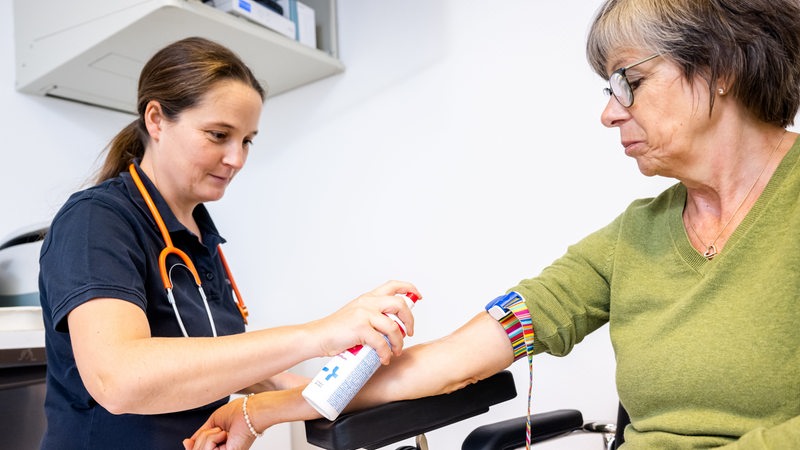 Eine Hausärztin desinfiziert den Arm einer Patientin (Symbolbild)