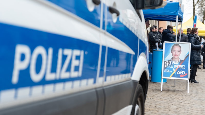 Ein Polizeiauto neben dem Wahlkampfstand der AfD mit einem Plakat der Spitzenkandidatin Alice Weidel