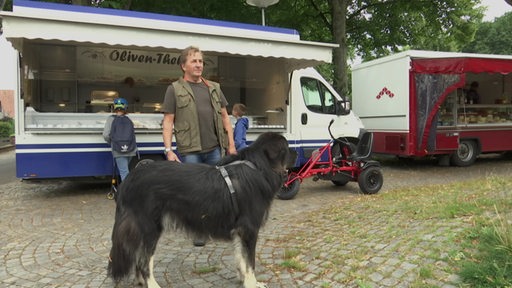 Der Einwohner Kai Struck steht mit seinem Hund auf dem Wochenmarkt in Arbergen