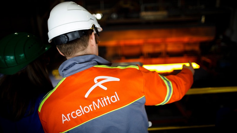 Ein Mitarbeiter der ArcelorMittal GmbH steht im Warmwalzwerk und schaut auf einen Ofen. 