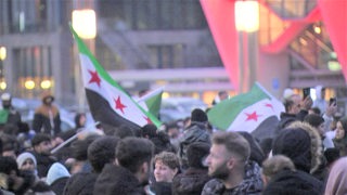 Menschen stehen mit syrischen Fahnen auf der Bremer Bürgerweide.