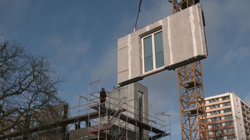 Ein Kran hebt eine Fertigwand bei der Baustelle des Auszubildendenwohnhauses an