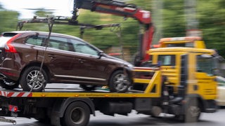 Ein Abschleppwagen mit einem Volvo fährt über eine Straße.