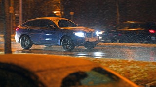 Ein Auto fährt bei Schnee und Glätte über eine Straße