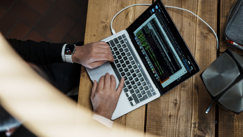 Zwei Männerhände über einer Laptop-Tastatur aus der Luft aufgenommen