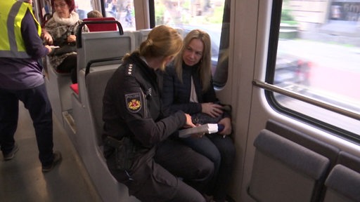 Eine Polizistin spricht mit einer Fahrgästin in einer Bahn.