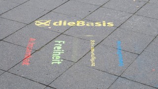 Gesprühte Wahlwerbung der Partei Die Basis auf einem Berliner Gehweg.