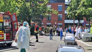 Vor dem Bassumer Krankenhaus versammeln sich mehrere Feuerwehrmänner und Krankenpfleger.