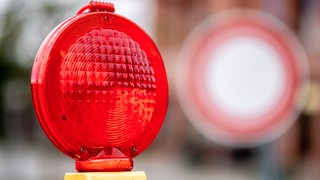 Eine rote Warnleuchte hängt an einer Baustelle vor einem Verkehrsschild