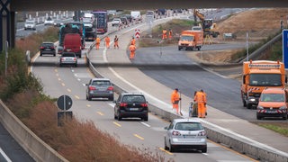 Bauarbeiter stehen in einer Baustelle auf der Autobahn A7.