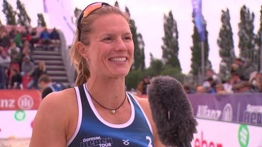 Die Beachvolleyballspielerin Kim van de Velde lächelt beim Interview.
