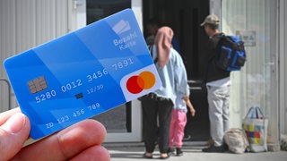 Eine Fotomontage zeigt im Vordergrund eine Bezahlkarte, während im Hintergrund ein Mann, eine Frau und ein 
