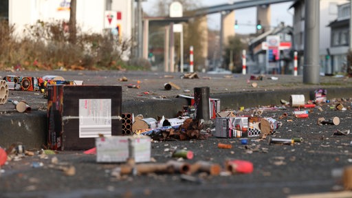 Auf einer Straße liegen zahlreiche Reste von Böllern und anderem Silvester-Feuerwerk-