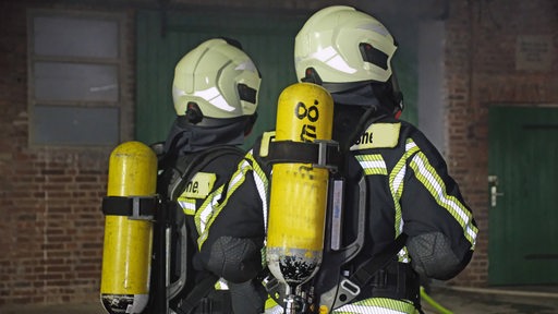 Zwei Feuerwehrleute stehen vor einem Stall.