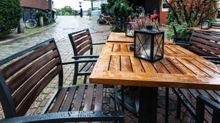 Ein nasser Tisch steht im Regen.
