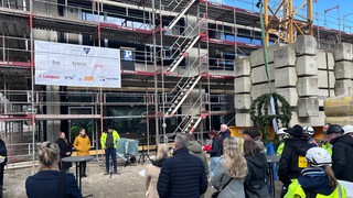 Mehrere Menschen stehen beim Richtfest um den Neubau einer Grundschule in Bremerhaven.