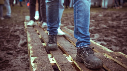 Besucher laufen auf dem matschigen Breminale-Gelände am Osterdeich über Holzstege