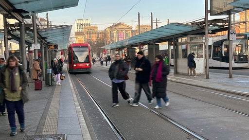 Menschen warten an den Haltestellen der BSAG am Bremer Hauptbahnhof während eine Bahn einfährt.