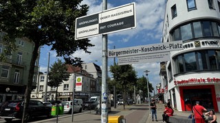 Man sieht das Straßenschild des Bürgermeister-Koschnick Platzes. Im Hintergrund ist die Sparkasse Bremen.