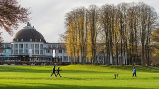 Walker und Jogger bei Sonnenschein vor dem Parkhotel im Bürgerpark im November 2024