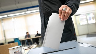 Eine Person wirft einen Wahlzettel in einer Wahlurne in einem Wahllokal in Bremen.