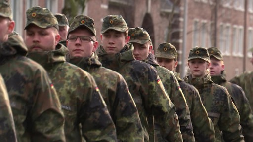 Eine Reihe Bundeswehrsoldaten marschieren hintereinander her.