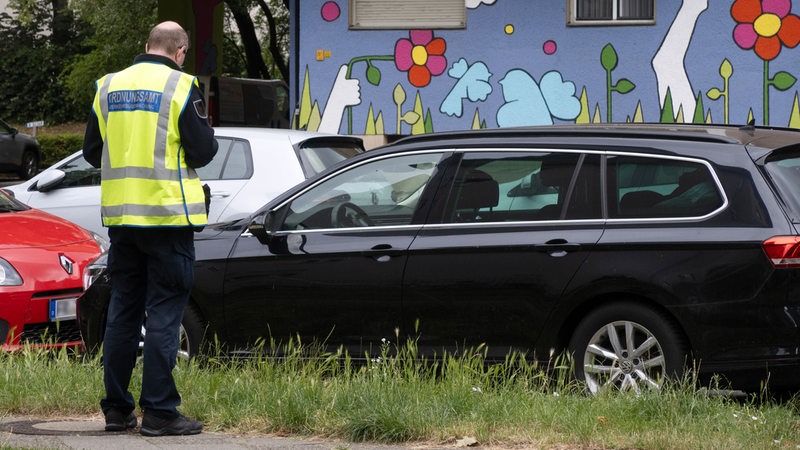 Ein Mitarbeiter des Ordnungsamtes schreibt einen Falschparker auf.