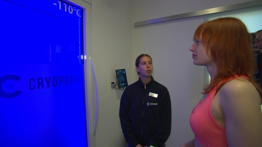 Die Reporterin Maike Evers-Schmidt steht mit einer Mitarbeiterin von Cyropoint vor der Kältekammertür.