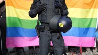 Ein Polizist steht vor einer Regenbogenfahne während eines Umzuges zum Christopher-Street-Day (CSD).