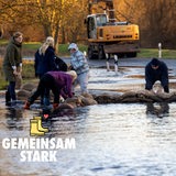 Menschen stapeln Sandsäcke.