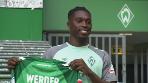 Werder Bremens Neuzugang Derrick Köhne hält das Werder Trikot in den Händen.