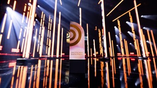 Auf einer Bühne steht eine Trophäe mit der Aufschrift "Deutscher Radiopreis".