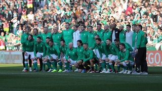 Fußballer posieren in zwei Reihen für ein Gruppenfoto.