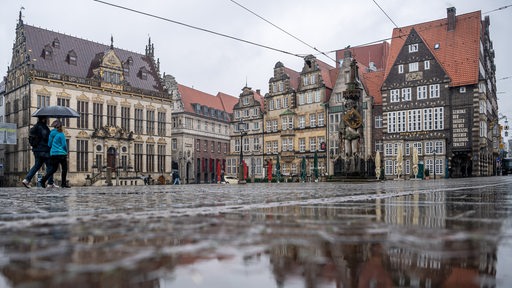 Der Marktplatz spiegelt sich in einer Regenpfütze. 