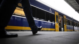 Eine Person am Bahnsteig vor einer Nordwestbahn.