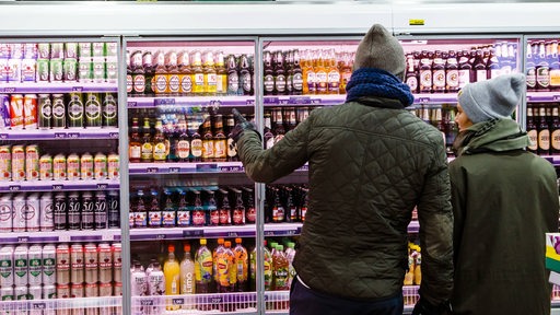 Zwei Menschen kaufen Bier in einem Kiosk. Wegen Corona soll das Alkohol-Verkauf weiter eingeschränkt werden.