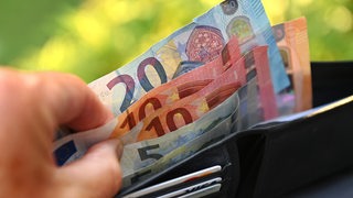 Eine Hand zählt Euronoten in einer Geldbörse (Symbolbild)