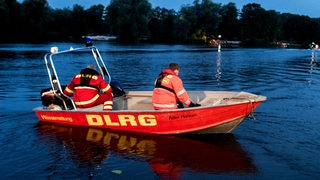 Helfer der DLRG sind mit einem Boot auf einem See unterwegs.