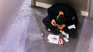 Ein Junkie raucht Heroin von einer Folie in einer U-Bahn-Haltestelle. 