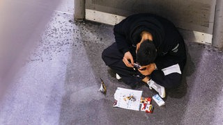 Ein Junkie raucht Heroin von einer Folie an einem öffentlichen Platz.