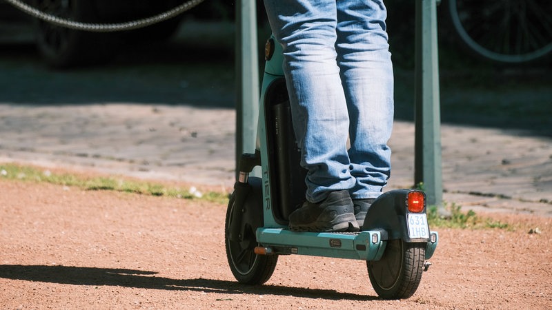 Eine Person fährt auf einem grünen E-Roller.