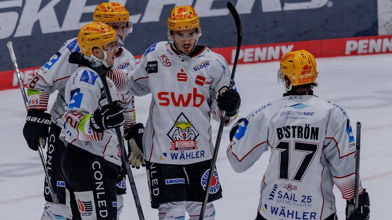 Eishockey-Spieler der Fischtown Pinguins kommen auf dem Eis nach einem Treffer zusammen.