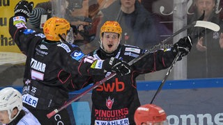 Eishockey-Spieler Justin Büsing von den Fischtown Pinguins reißt nach einem Tor jubelnd die Arme hoch.