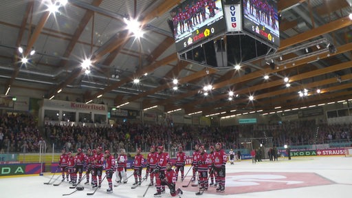 Die Eishockey-Mannschaft der Fischtown Pinguins steht nach dem Sieg im Champions-Spiel auf dem Eis und lässt sich von ihren Bremerhavener Fans feiern.