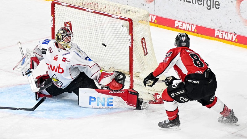 Der Kölner Eishockeyspieler Alex Grenier schießt den Puck ins Tor von Kristers Gudlevskis.