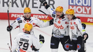 Eishockey-Spieler um Jan Urbas und Colt Conrad von den Fischtown Pinguins bejubeln gemeinsam überschwänglich einen Treffer auf dem Eis.