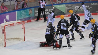 Eishockey-Spieler der Fischtown Pinguins schauen konsterniert, als ein Spieler der Kölner Haie den Puck in ihr Tor schießt.