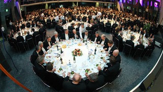 Viele Männer sitzen beim Abendessen.